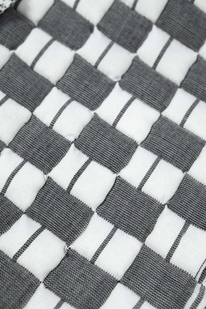 Close-up of the quilted Sujani throw blanket weave in soft black and white