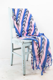 Palm ikat blanket in blue and pink draped over a chair