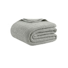 Oversized snug bed blanket draped across modern bed