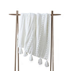 Braided Pom Pom Throw folded on sofa with pom pom detail visible