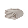 Snug Muslin Bed Blanket draped across bed with fringed edge