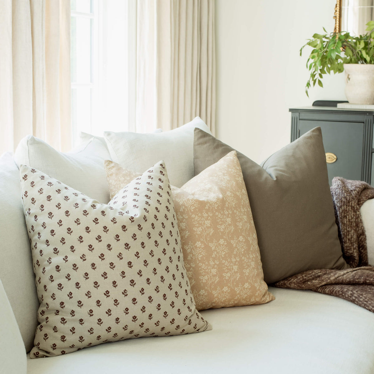 Fleur tan botanical pillow with a burgundy ditsy pillow on a sofa