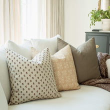 Fleur tan botanical pillow with a burgundy ditsy pillow on a sofa