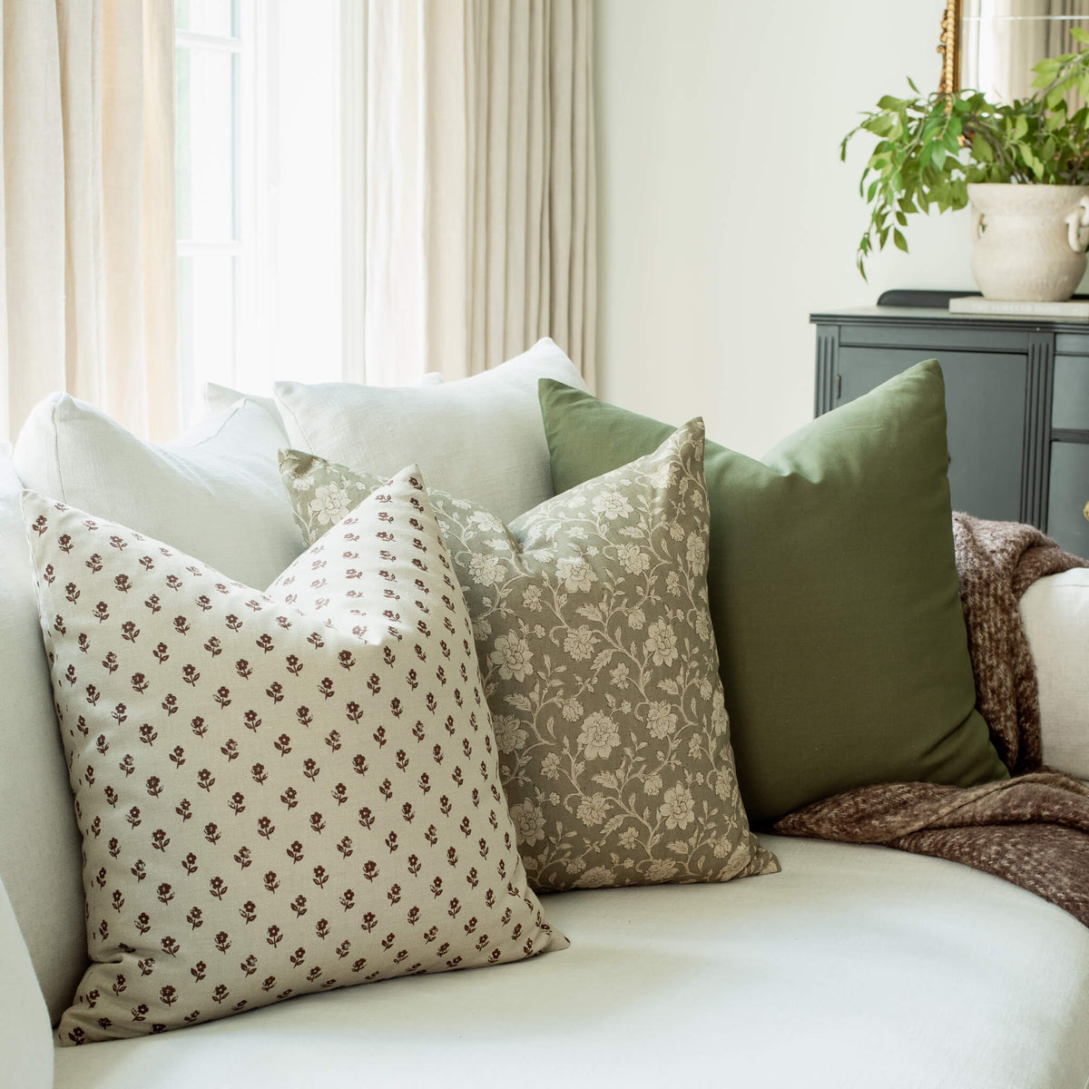 Pippa brown ditsy pillow with taupe floral and olive pillows on a sofa