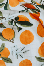 47x47 cotton muslin swaddle folded to show orange fruit design