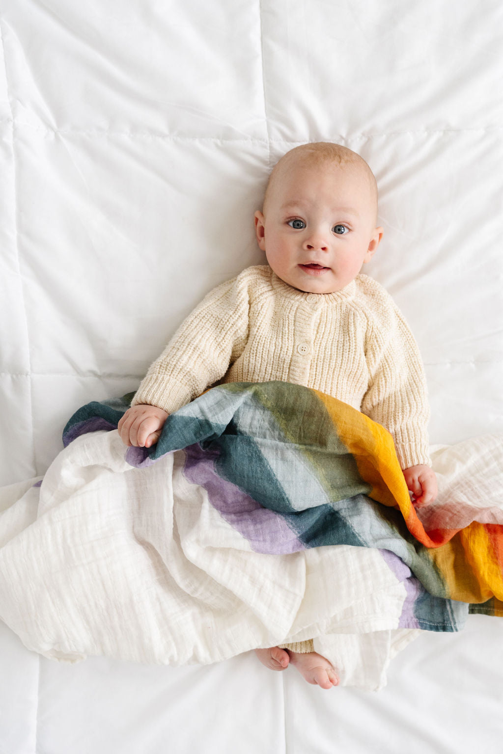 Clementine Kids Rainbow swaddle styled in nursery