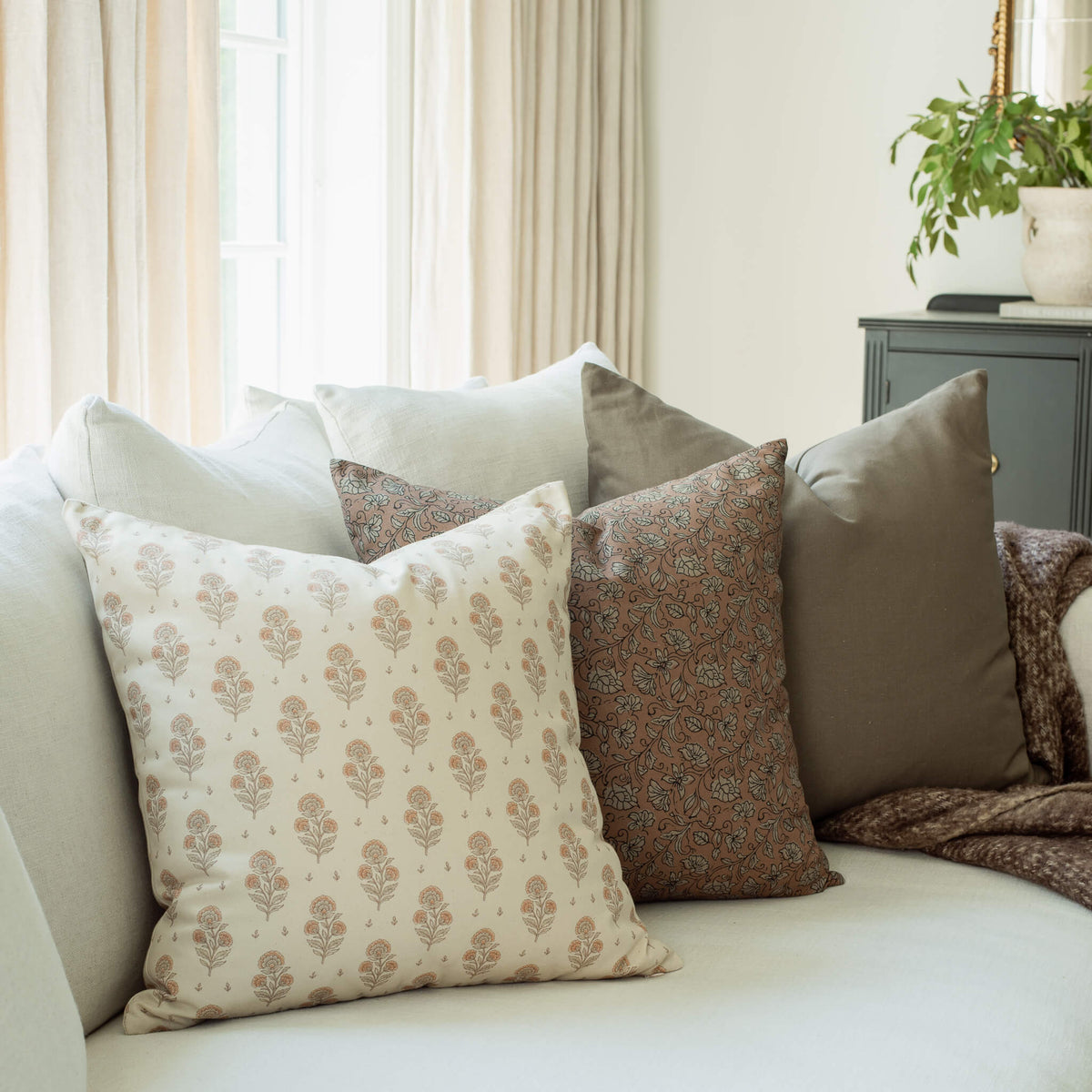 Anais blush floral pillow with a terracotta paisley pillow on a sofa