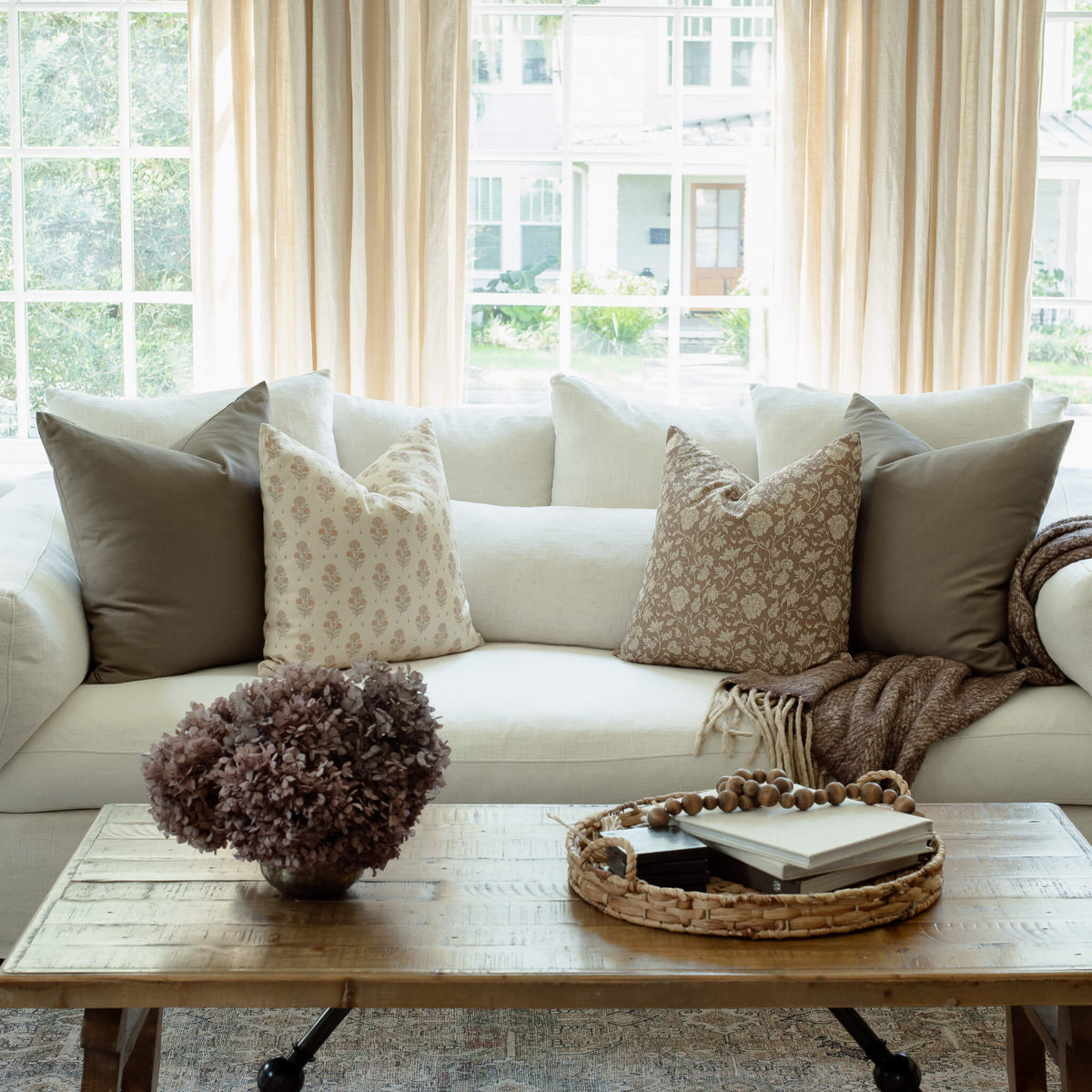 Anais floral pillow with taupe textured pillows on a sectional
