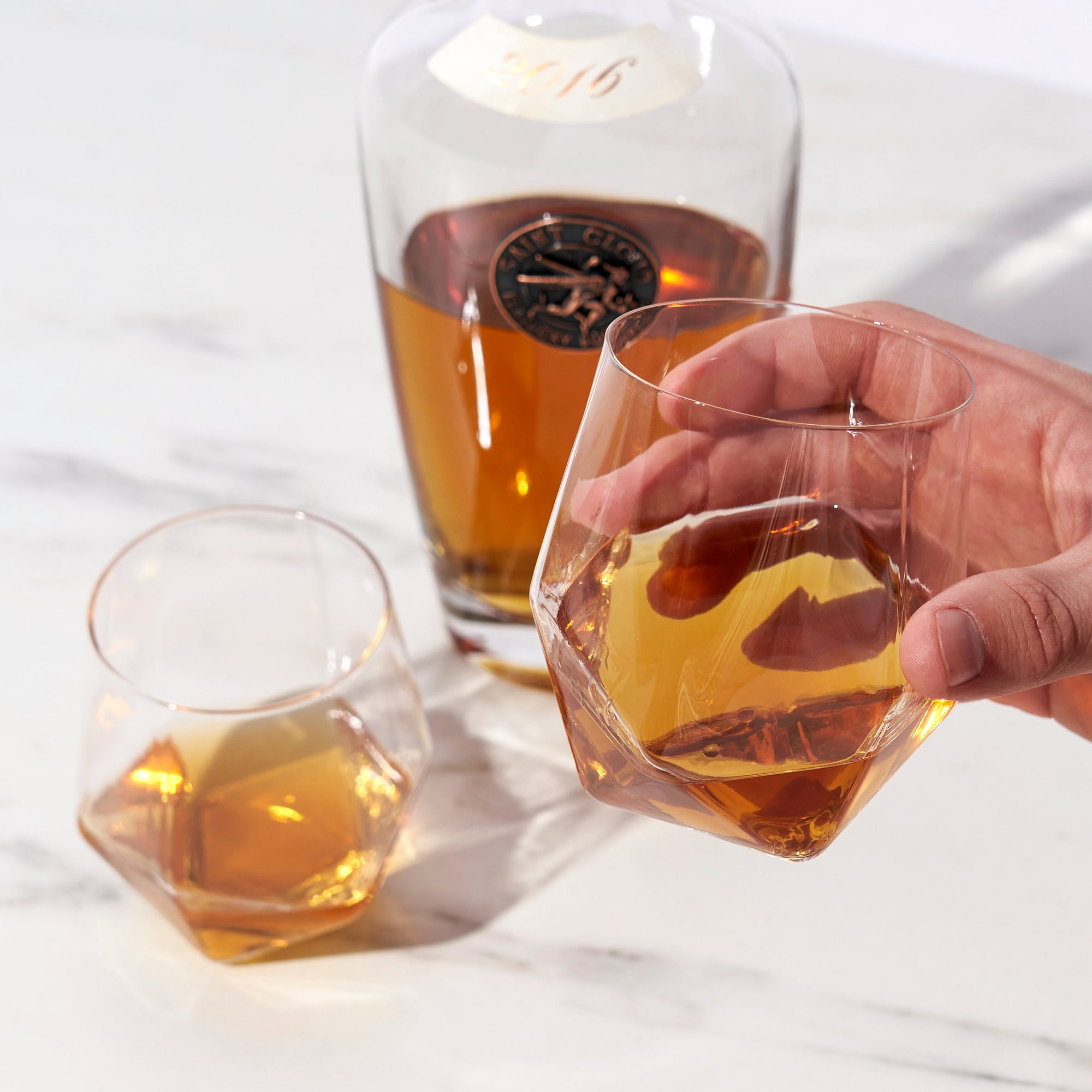 Close-up of angled crystal tumbler with whiskey and ice