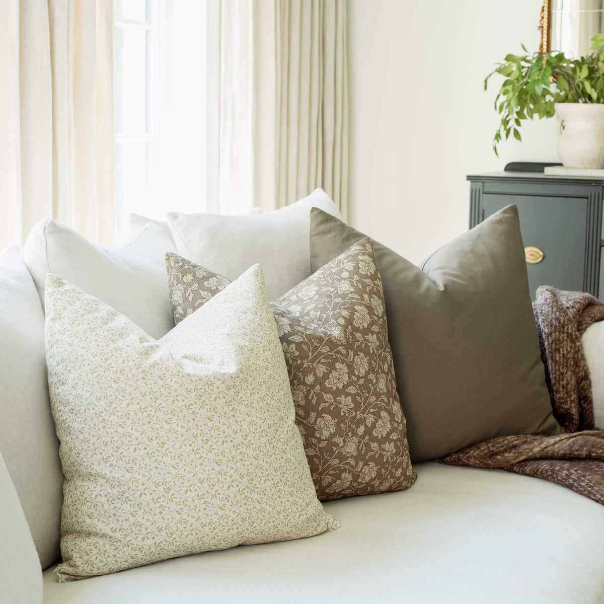 Mila ivory floral pillow with taupe floral pillows on a sofa