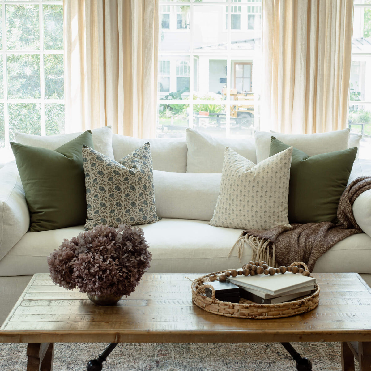Leme olive pillow with navy floral and ivory ditsy pillows on a neutral sofa
