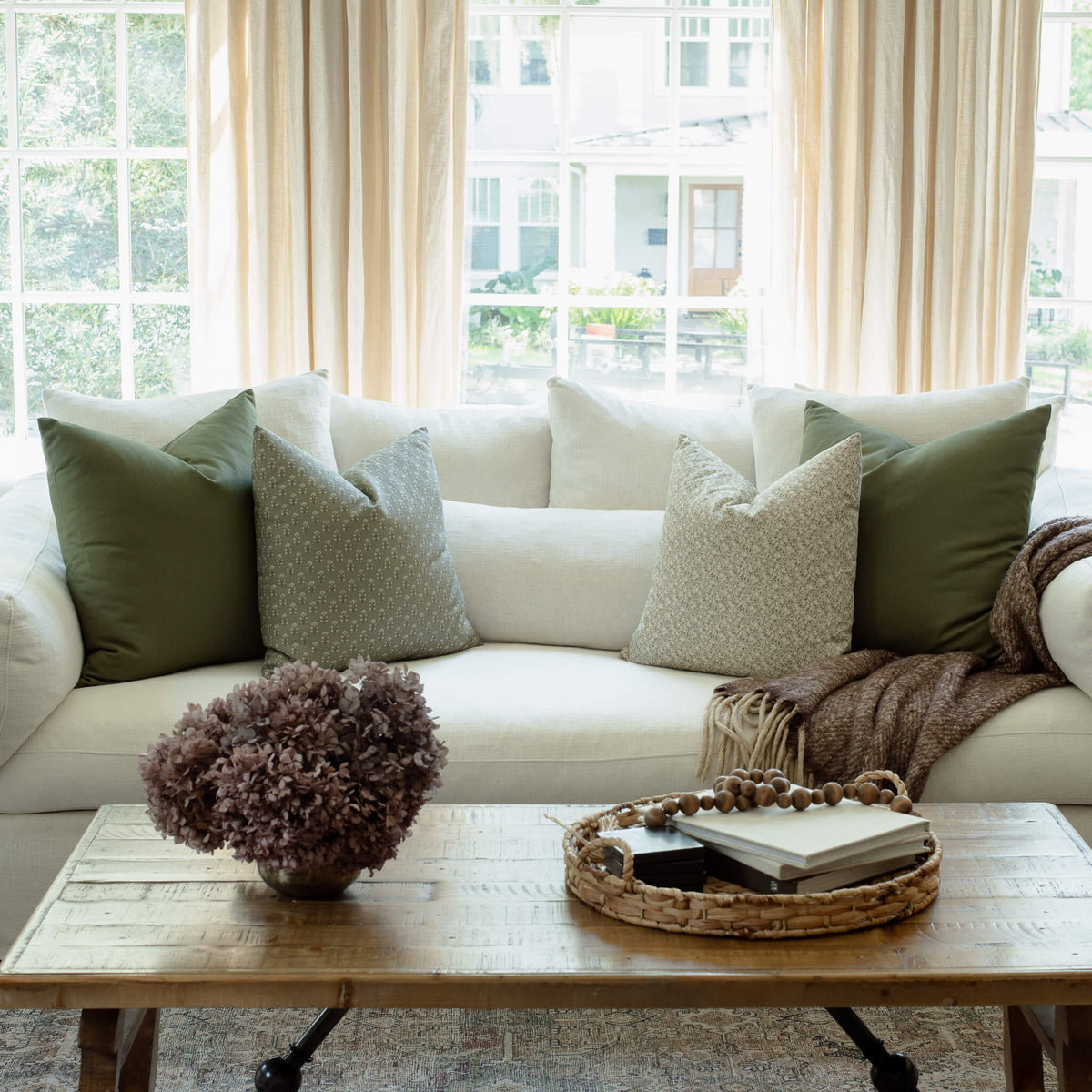 Sylvie sage pillow with navy and olive pillows on a neutral sectional