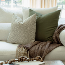 Sylvie sage floral pillow styled on a neutral sectional