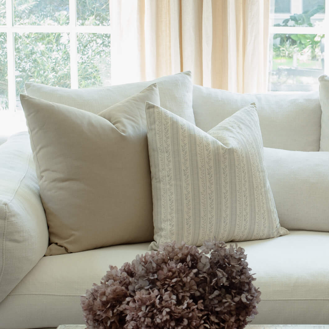 Faye blue vine stripe pillow styled on a neutral sectional