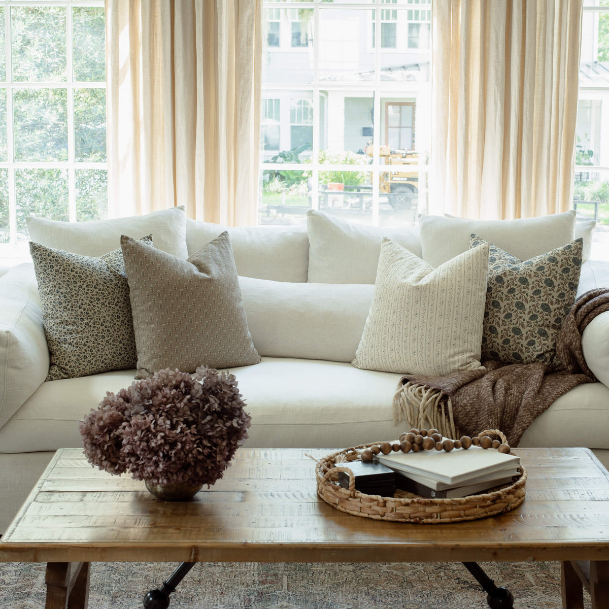 Adeline blue floral pillow with tan and ivory striped pillows on a neutral sofa