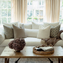 Adeline blue floral pillow with tan and ivory striped pillows on a neutral sofa