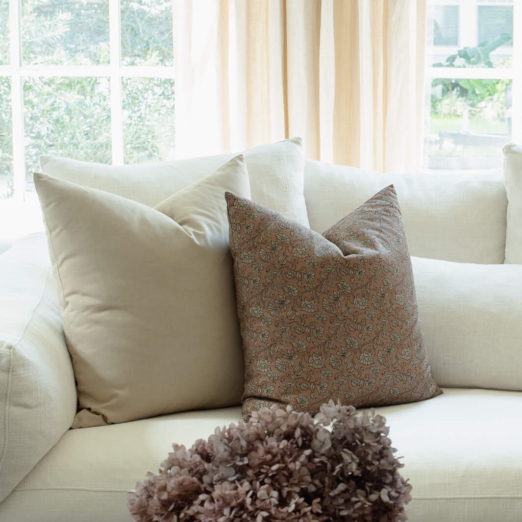 Odette terracotta pillow with tan botanical and cream block print pillows on a sectional