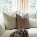 Odette terracotta pillow with tan botanical and cream block print pillows on a sectional