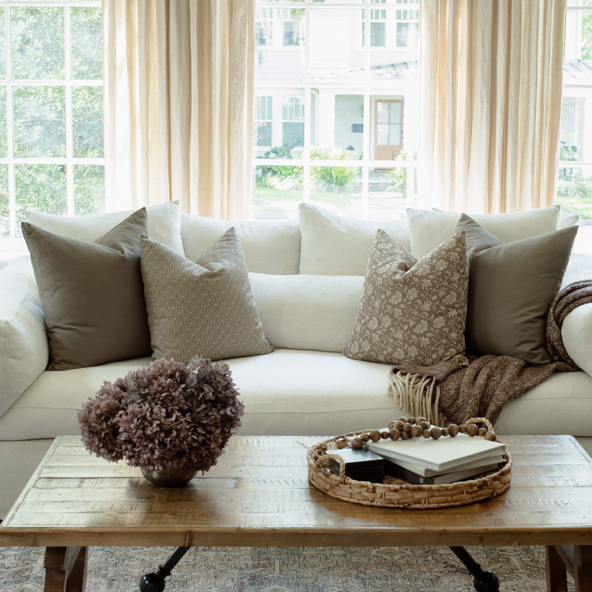 Clara taupe botanical pillow styled on a neutral sectional