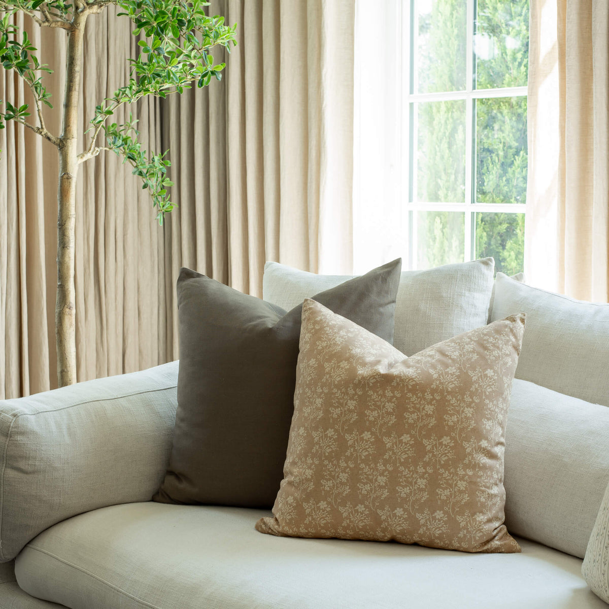 Fleur tan floral throw pillow styled on an organic modern sofa