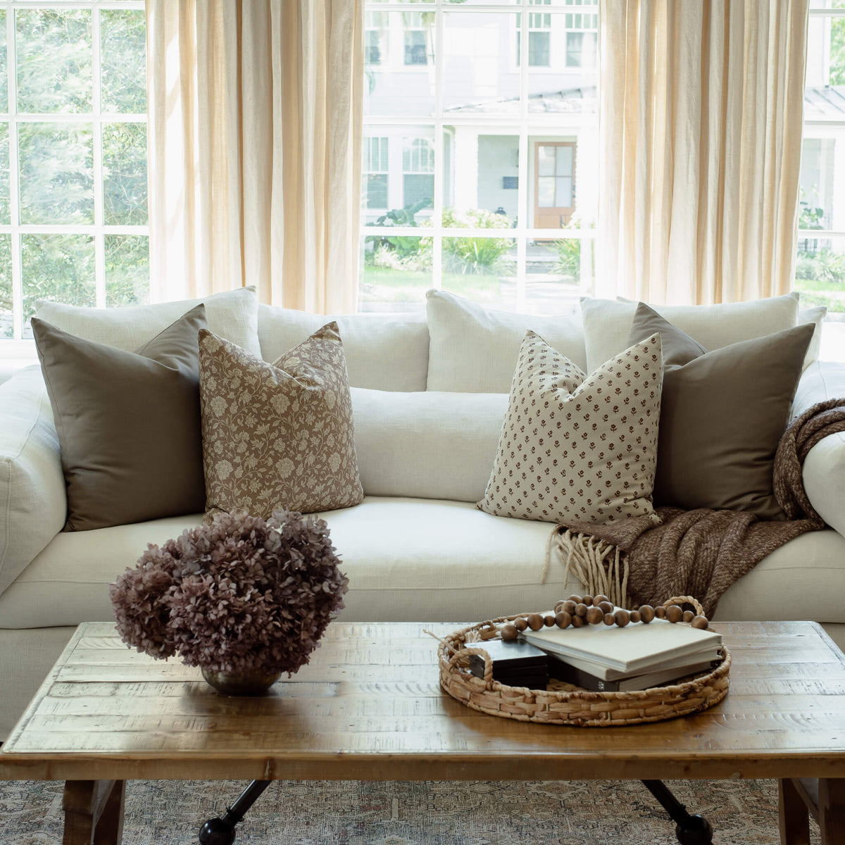 Madeleine taupe floral pillow with burgundy print pillows on a neutral sofa